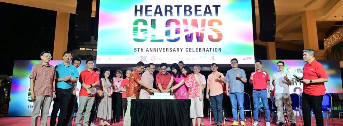 Group cuts cake at "Heartbeat Glows 5th Anniversary Celebration" event onstage.